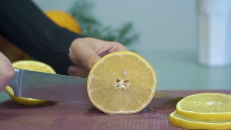 Woman-slicing-yellow-lemon-on-chopping-board-closeup-slow-motion