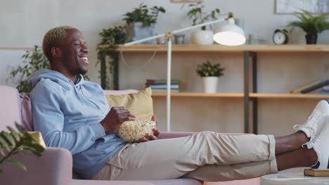 black man laughing and watching movie at home