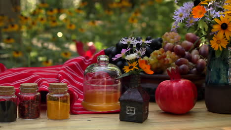 thanksgiving table with spice jars, bowl of grapes, red pomegranate and vase of with flowers