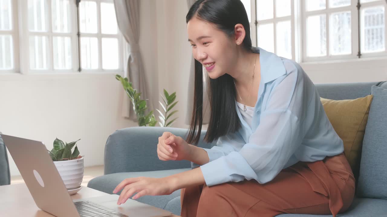 Asian Female Using Laptop And Celebrates In Living Room, Video In 4K