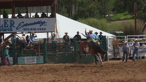 Evergreen-Rodeo-Colorado-Mountain-tradition-professional-cowboys-horse-bull-riding-USA-bucking-follow-pan-to-the-right-American-saddle-fans-crowd-cheering-event-hot-summer-day