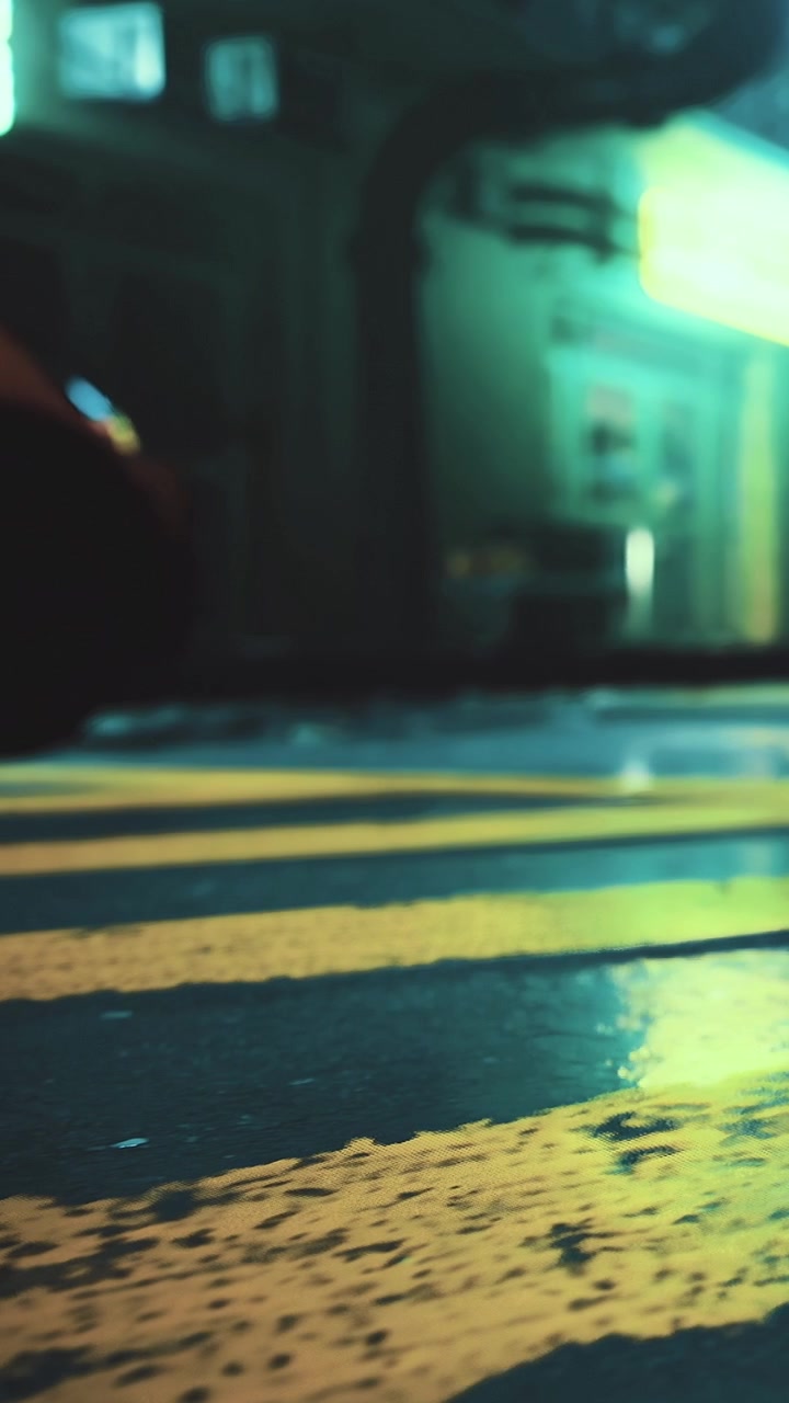 Strada bagnata con linee gialle e luci al neon di notte in una città