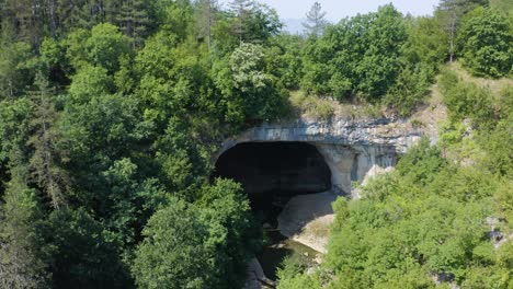 gods bridge cave entrance with lush green forest in summer in vratsa, bulgaria