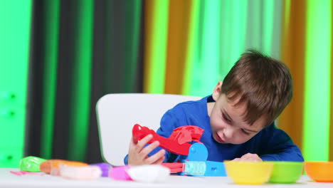 cute smiling baby boy presses the mold machine. lovely toddler opens the device and winks at the result plasticine.