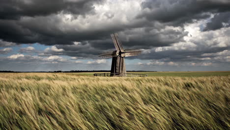 old wooden windmill in a wheat field under a stormy sky