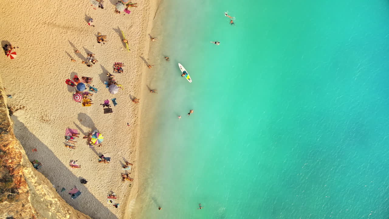 Vista aerea da drone della costa del Mar Ionio di Zante, Grecia. Spiaggia con persone che si riposano e nuotano, acqua blu. Tramonto