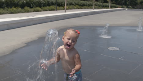 little kid having fun with fountain jet