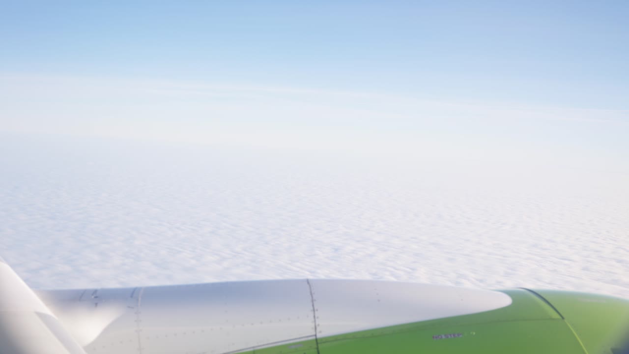 Smooth glide over dense cloud tops with glowing sunlight spreading across the expansive sky, POV from airplane window