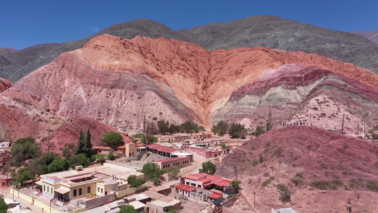 drone volando hacia adelante revelando un pueblo al pie de los cerros de siete colores en la provincia de jujuy, argentina