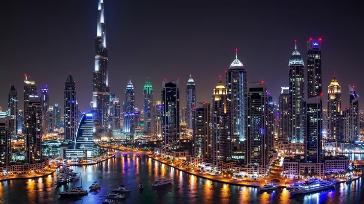 Dubai Marina featuring a vibrant cityscape at night, with the illuminated Burj Khalifa rising among modern skyscrapers and reflecting in calm waters below