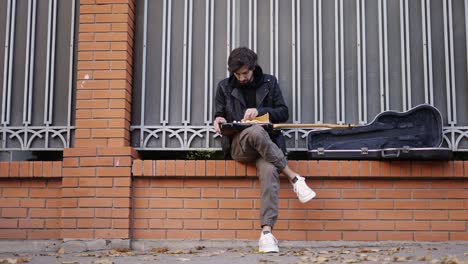 man take care of the guitar sitting on the street