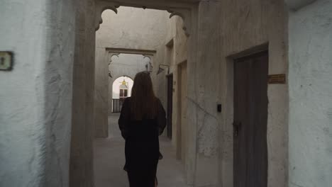 woman dressed in black outfit is walking through old building in dubai emirates