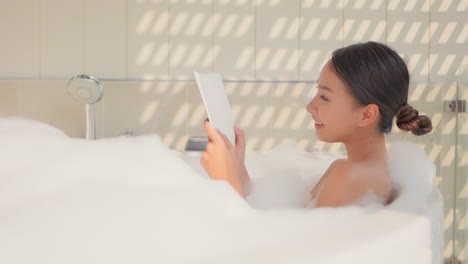 Schöne-Asiatische-Frau,-Die-Ein-Buch-In-Einer-Schaumigen-Badewanne-Liest