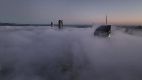 Aerial-shot-above-a-cloudy-foggy-Brisbane-City,-with-only-the-tops-of-sky-scrapers-being-visible