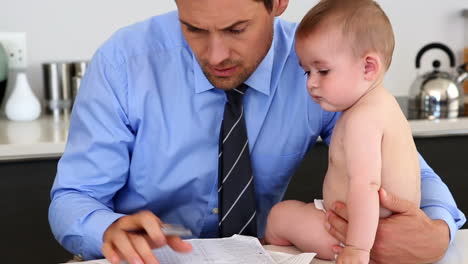 padre estresado calculando facturas con su bebé