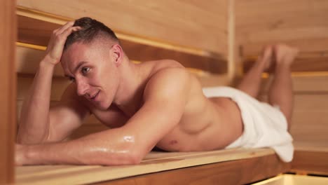guapo deportista se relaja en la sauna rusa