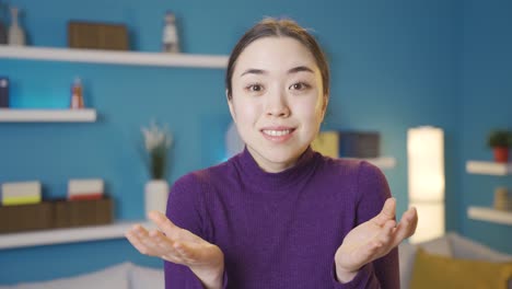 젊은 아시아 여성이 행복하고 혼란스럽게 카메라를 보고 있습니다.