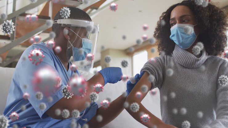 Animation of covid 19 cells over african american woman in face mask receiving vaccination