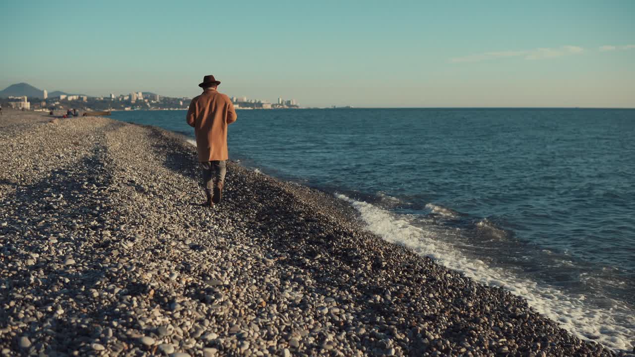 hombre caminando por una playa de guijarros
