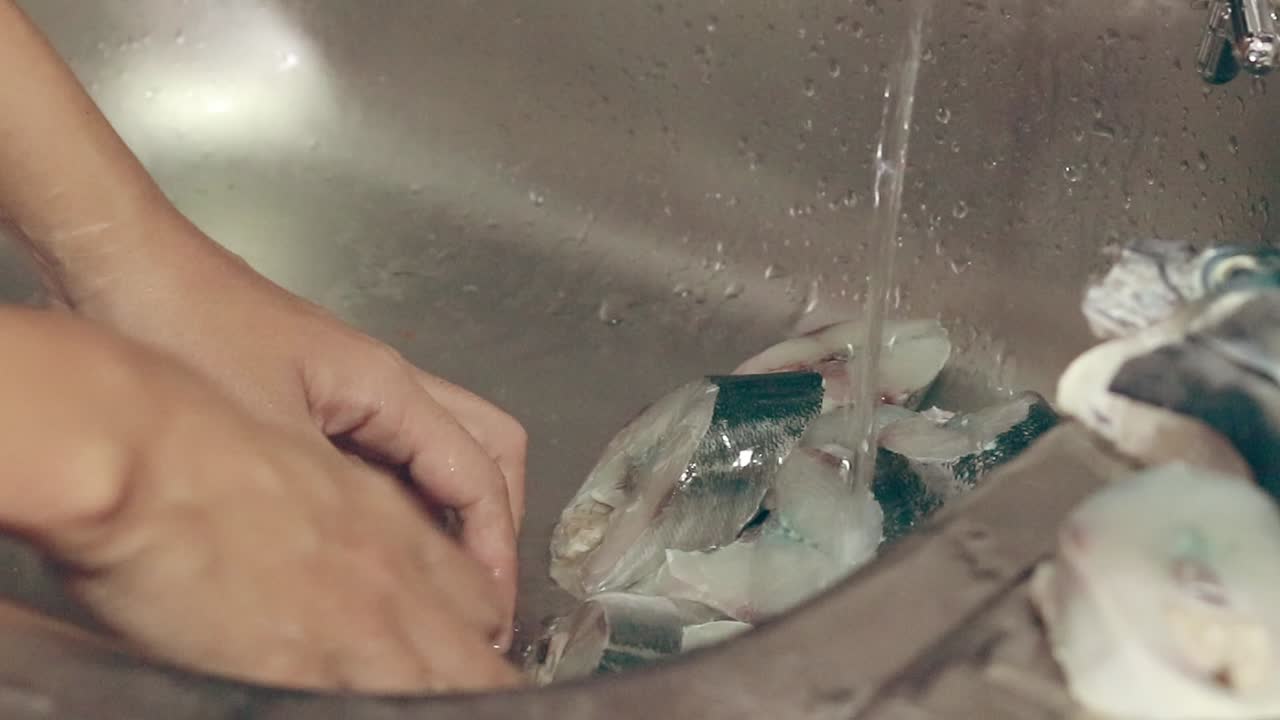 매일의 가정 생활의 솔직하고 평화로운 순간, 손이 어낸 생선을 싱크대에서 고 나중에 요리하는 것으로 나타납니다.