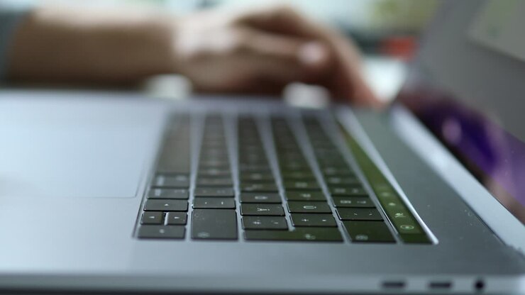 Close-up of a man's hand with a wedding ring working on the laptop