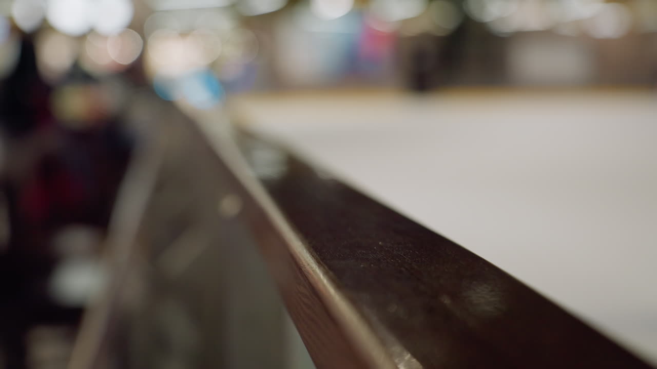 una vista sfocata di un'area sciistica con qualcuno che scia in abiti neri. questo video evidenzia l'ambiente dinamico e la ringhiera lucidata in primo piano