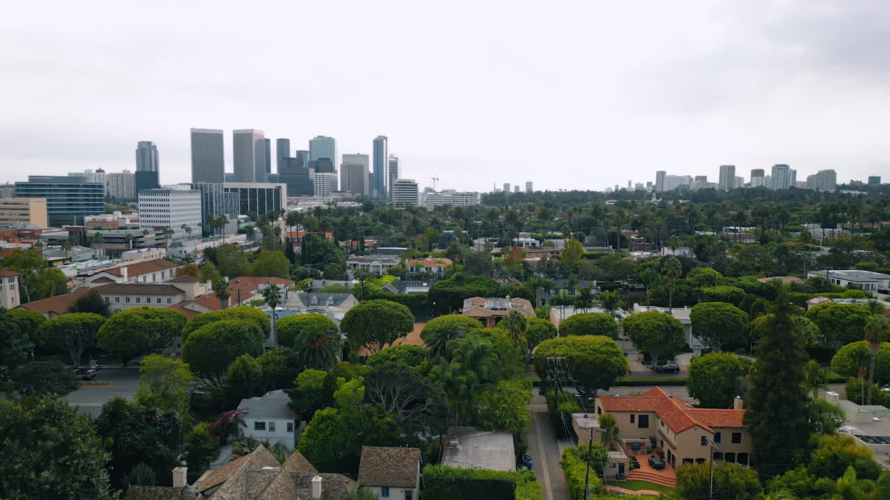 Luxurious villas in the lush greenery. Residential area in Los Angeles, California, USA. High-rise buildings at backdrop