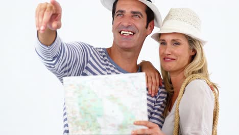 pareja sonriente mirando el mapa y apuntando contra un fondo blanco