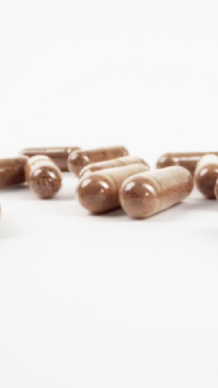 variedad de cápsulas de hierbas marrones sobre fondo blanco con enfoque selectivo