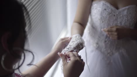 helping bride with her dress-glove