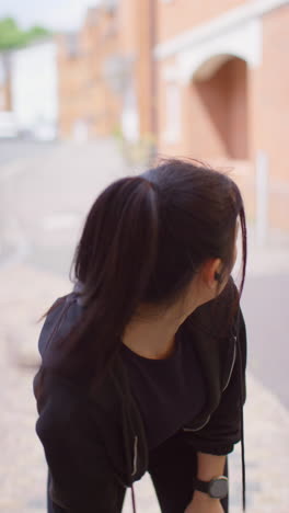 Vertical-Video-Of-Young-Woman-Exercising-Running-On-Urban-Street-Wearing-Wireless-Earbuds-Checking-Smart-Watch-2