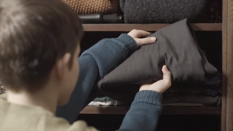 niño organizando ropa en un armario de madera