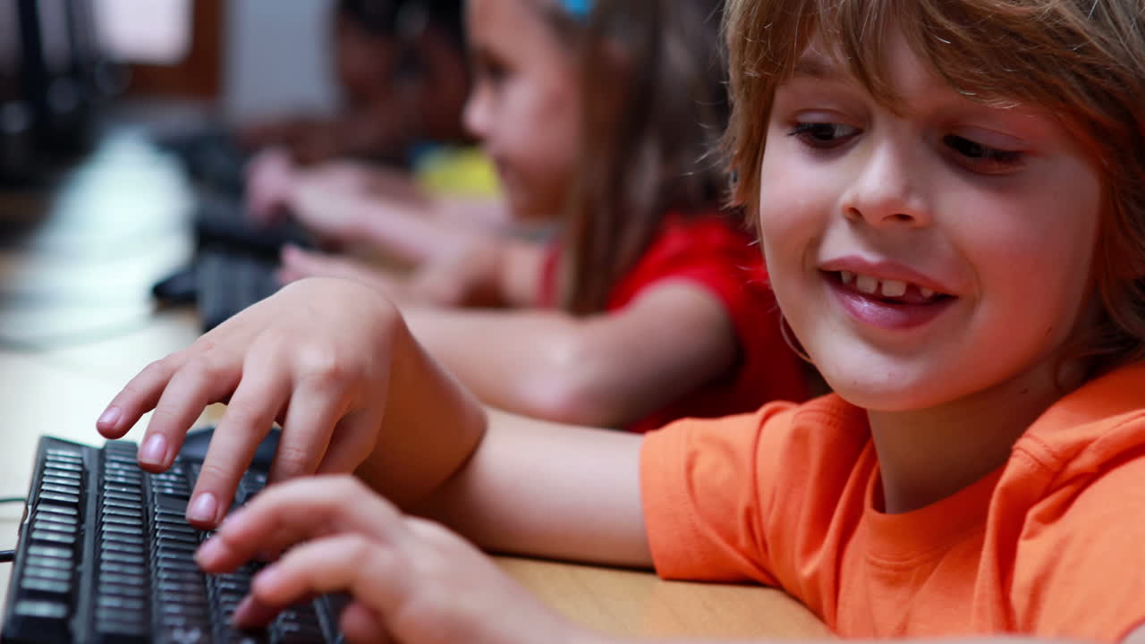 niño sonriendo a la cámara durante la clase de computadora