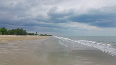 Cha-Am-Beach-in-Thailand-with-Low-Angle-Dolly-Shot-Along-the-Sand-with-Ocean-Waves