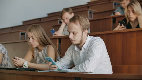 Grupo-Multiétnico-De-Estudiantes-Que-Utilizan-Teléfonos-Inteligentes-Durante-La-Conferencia.-Jóvenes-Que-Usan-Las-Redes-Sociales-Mientras-Estudian-En-La-Universidad.