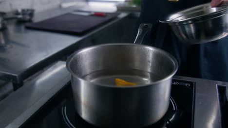 chef cook in apron puts ravioli in saucepan