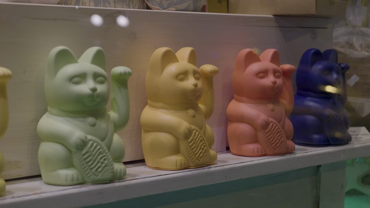 Colorful cat figurines with raised paws, featuring a red one actively engaged