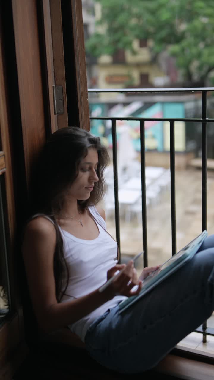mujer joven trabajando en la tableta en la ventana