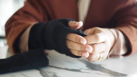 close-up of a woman's hands wearing a ring and a brown sweater.