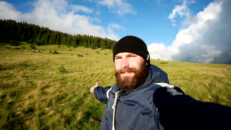 young man traveler makes selfie on background mountains