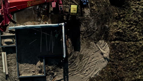 Turning,-straight-down-aerial-view-of-a-crane-placing-panels-at-a-construction-site