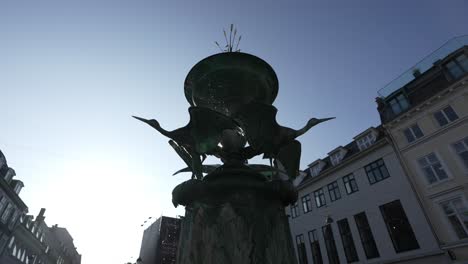 copenhagen's stork fountain, a low-angle view of the bronze sculpture on amagertorv square.