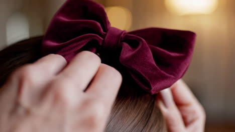 adjusting a maroon velvet hair bow