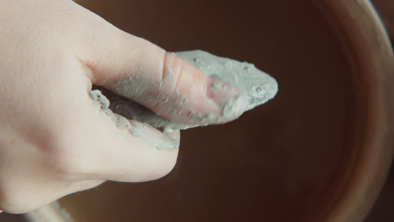 la mano del escultor lavando el raspador de arcilla
