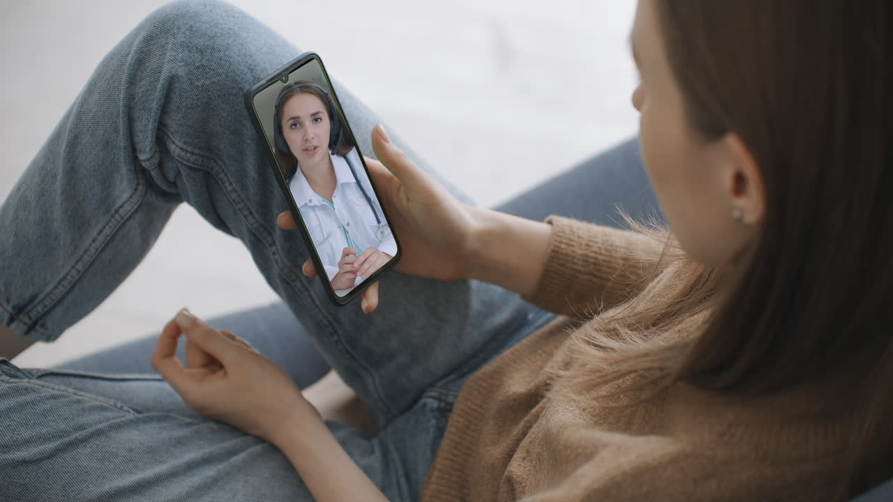 asistente médica usa casco blanco auriculares video llamando a un paciente distante en el teléfono inteligente. médico hablando con el cliente usando una aplicación telefónica de chat virtual. telemedicina servicios de atención médica remota