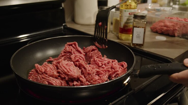 Seorang Wanita Mengurai Daging Giling yang Sedang Dimasak di Wajan Penggorengan