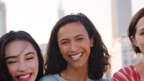 retrato de amigas reunidas en la terraza del techo para una fiesta con el horizonte de la ciudad en el fondo