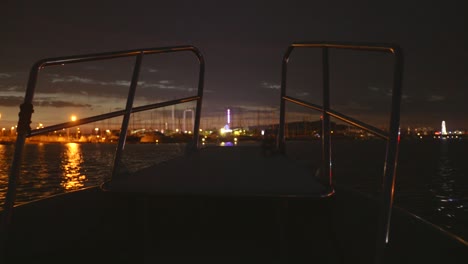 front pov view from a boat at night in agde, france, with city harbor lights glowing across the calm waters