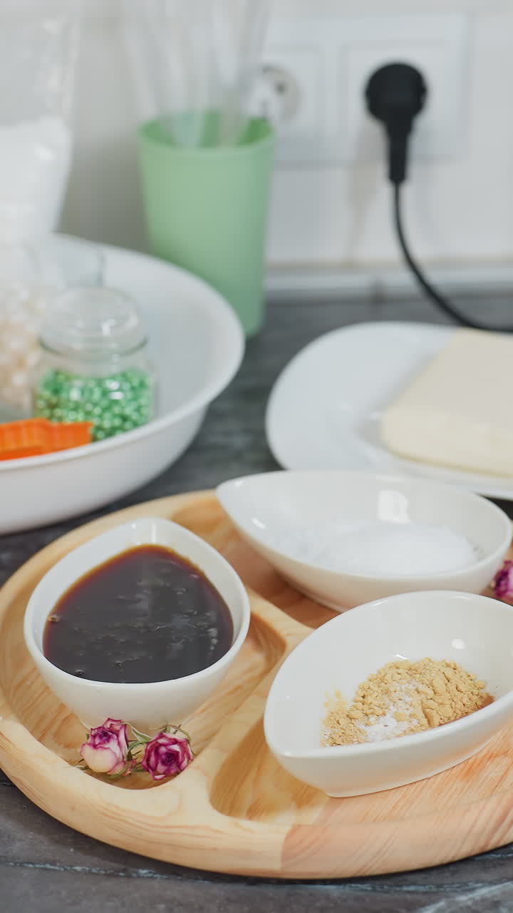 소스, 설탕 및 향신료가 들어있는 세라 그, 접시에 버터, 재료가 있는 유리 항아리 및 검은 대리석에 유리 비가 있는 목조 트레이를 특징으로 한 현대 주방 카운터의 클로즈업