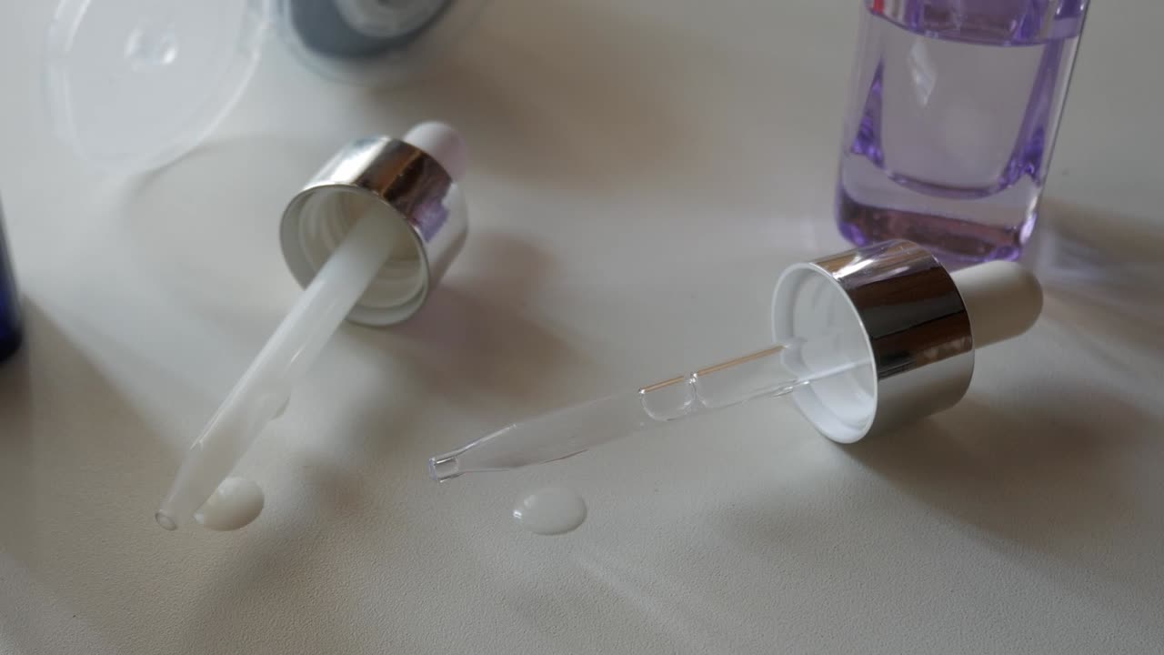 Two dropper bottles with hyaluronic acid and retinol serum on white table